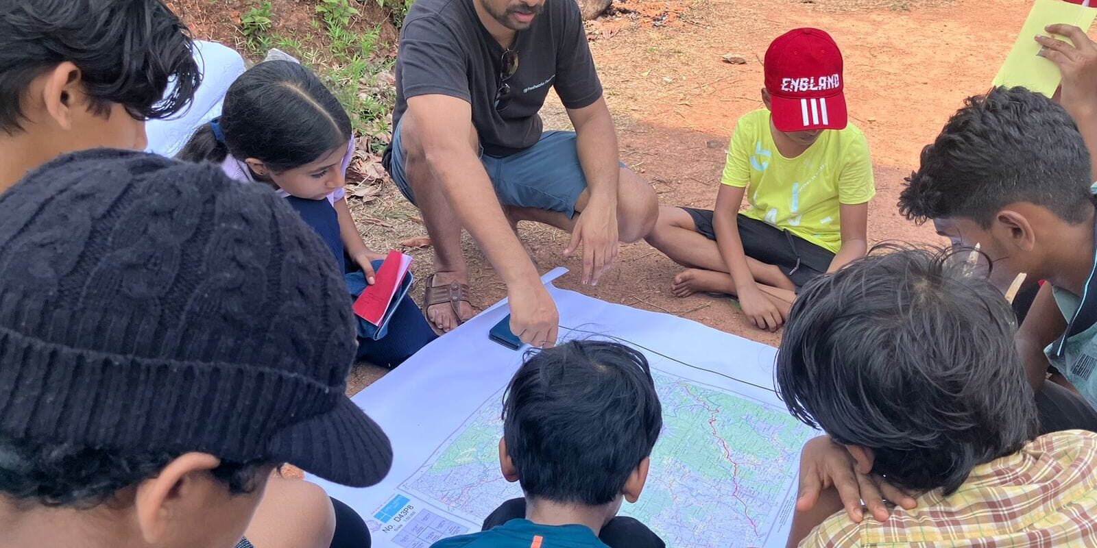Gautham with kids exploring an area with a map